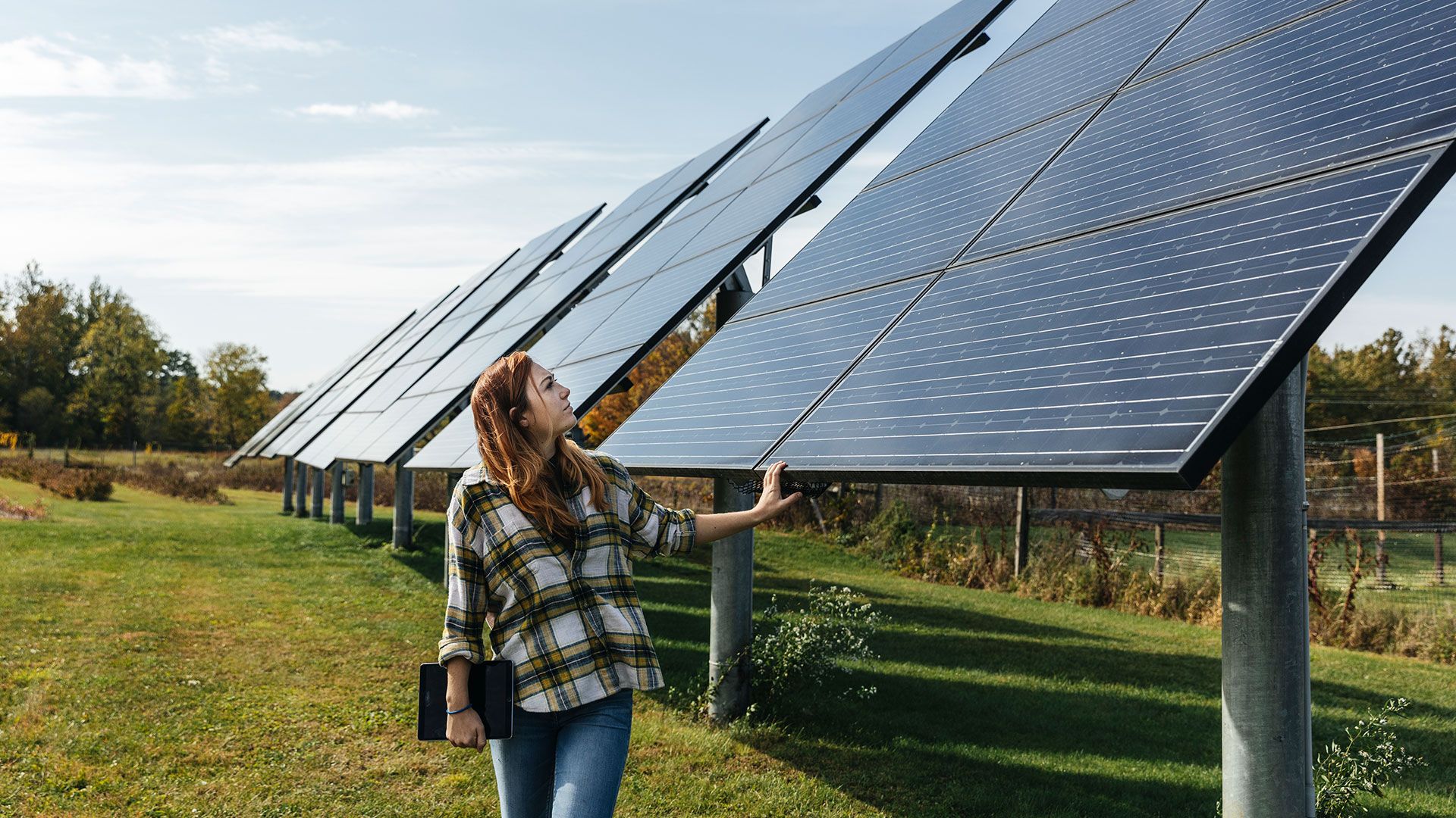 A woman walks past a solar farm. Barclays believes businesses have a role in tackling climate change
