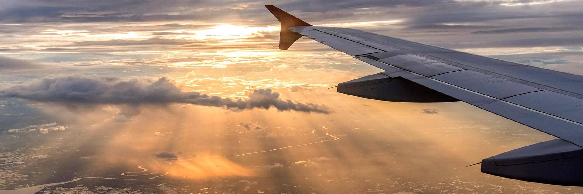 An aircraft wing is seen with the sun rising. Zero-emission hydrogen is the future of  air travel
