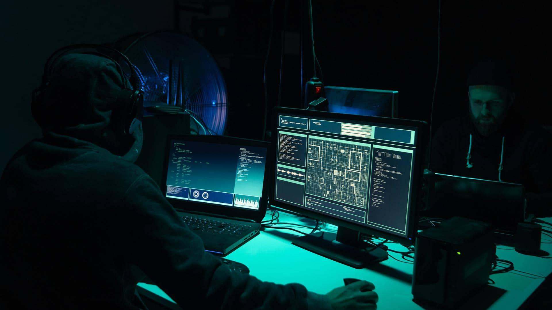 Two men looking at computer screens in the dark. Big game hunting puts treasuries at cyber fraud risk

