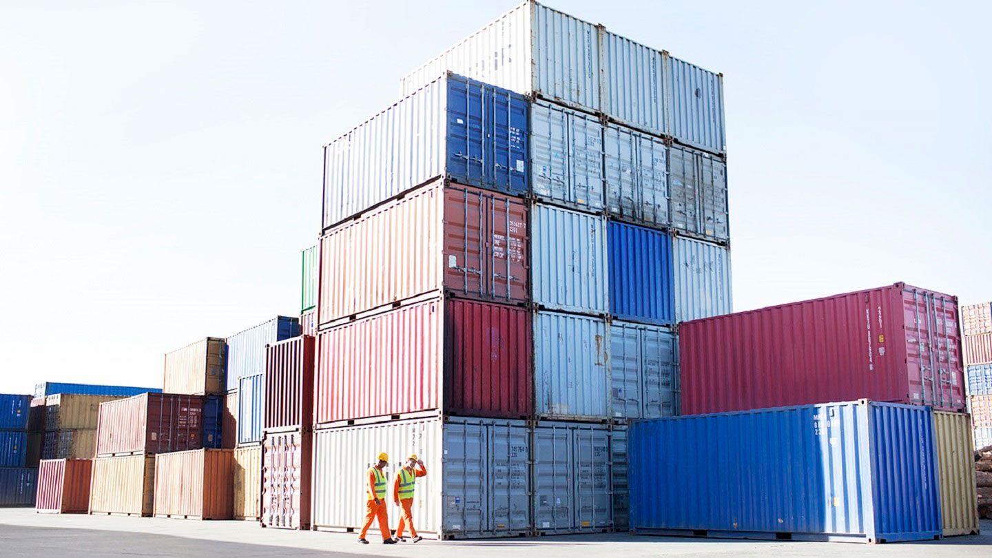 Two men walking through a container yard. An independent trade policy will help fasten trade deals.
